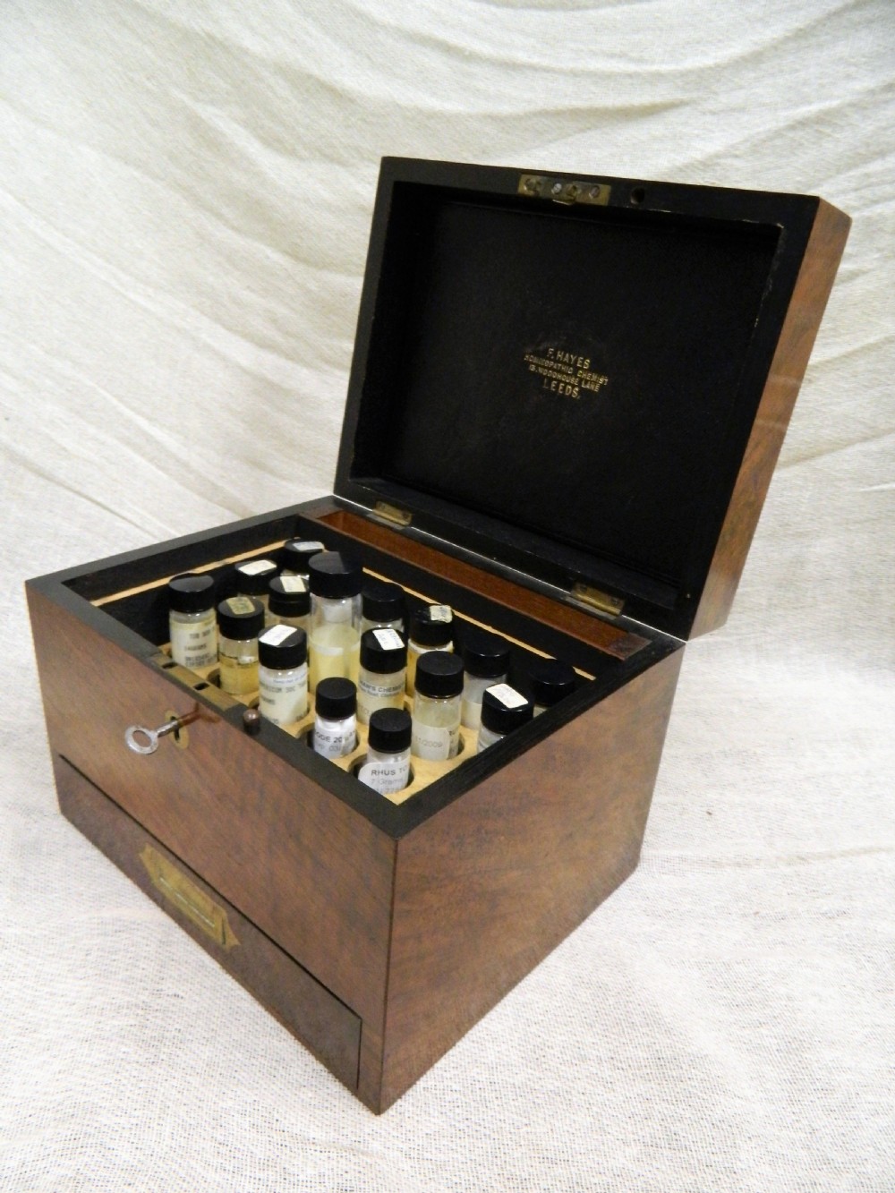 An opened Victorian mahogany apothecary chest displaying rows of glass medicine phials in fitted compartments and a lower drawer containing labelled bottles. View VI