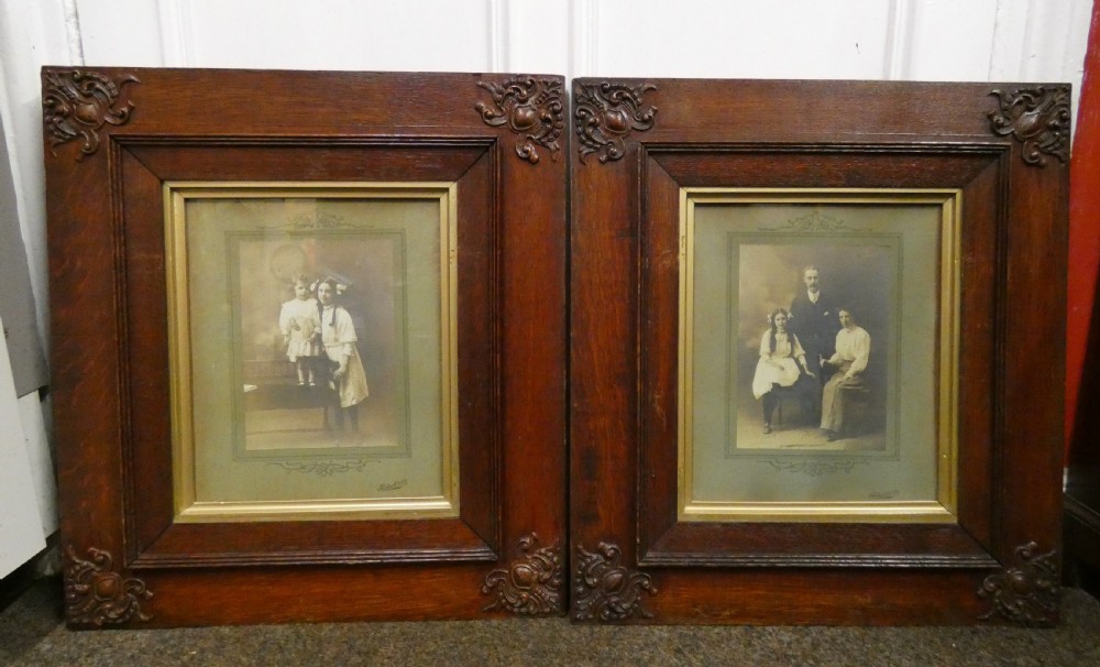 Pair of antique framed sepia family portraits housed within carved dark oak frames featuring inner gold gilt borders.