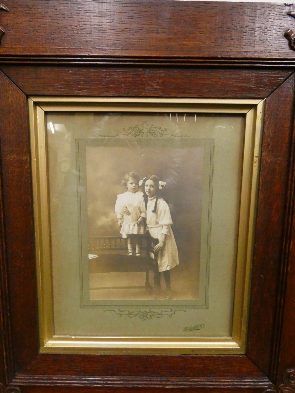 Pair of antique framed sepia family portraits housed within carved dark oak frames featuring inner gold gilt borders. View V