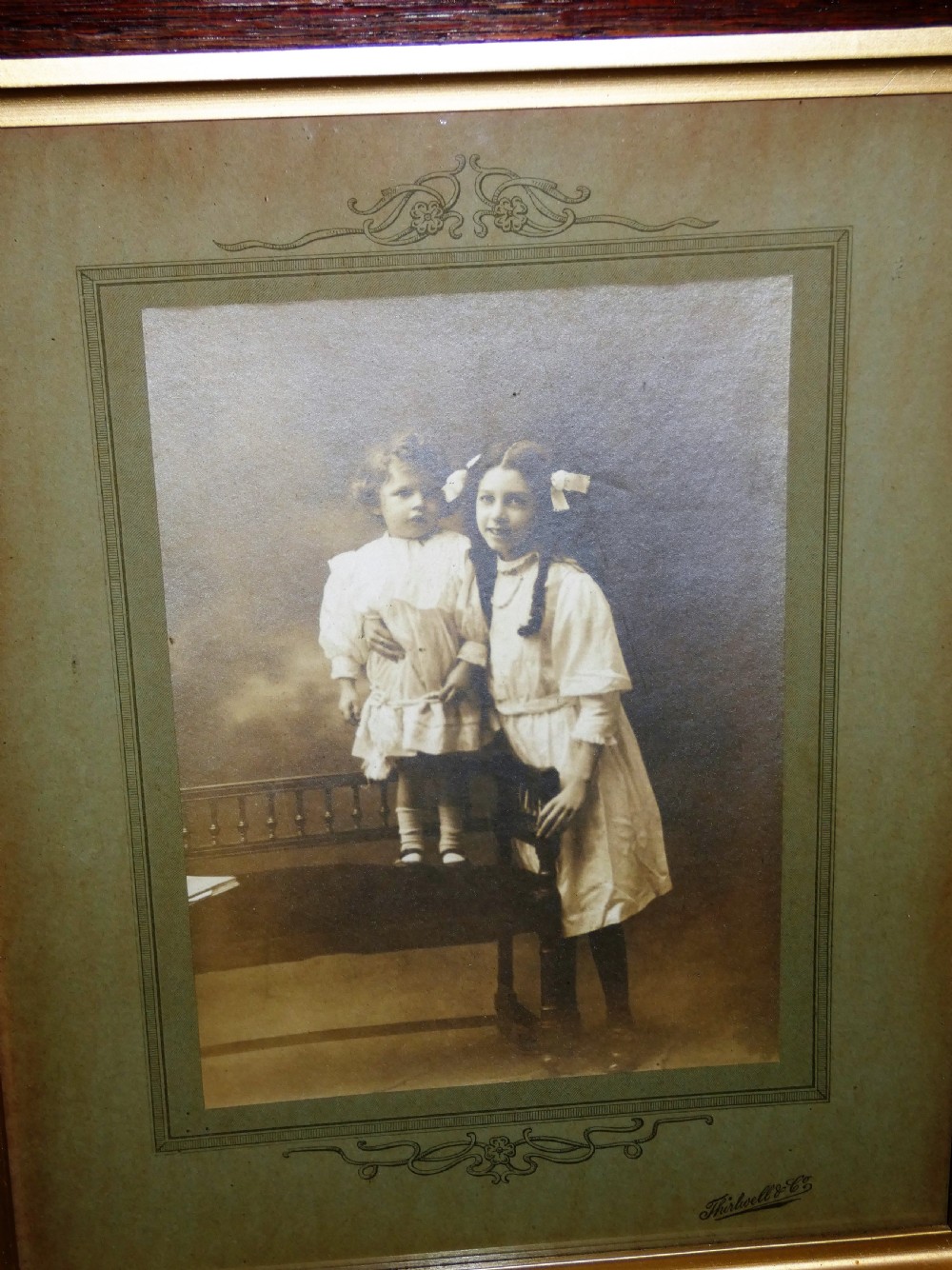 Pair of antique framed sepia family portraits housed within carved dark oak frames featuring inner gold gilt borders. View VII