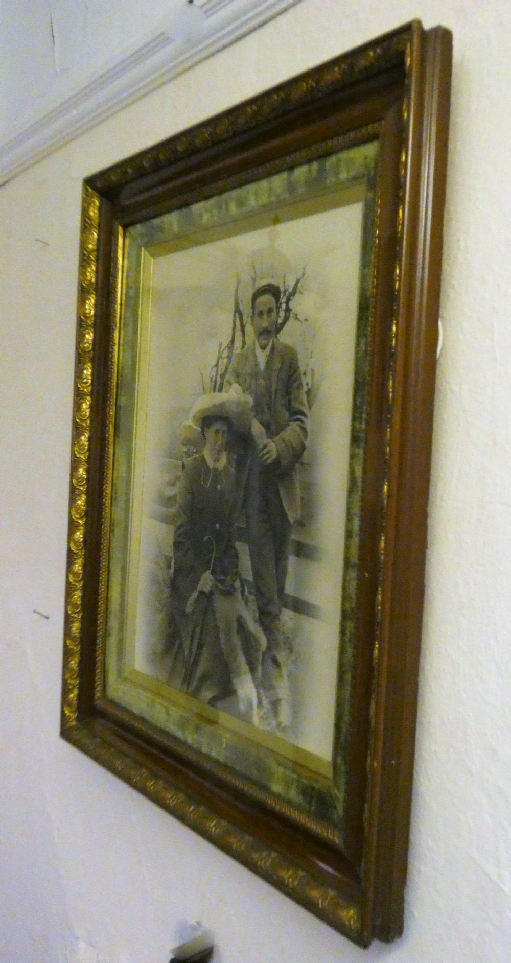 An antique monochrome portrait photograph of a man and woman displayed in a polished mahogany frame with a green velvet mount and decorative gilt slip. View IV