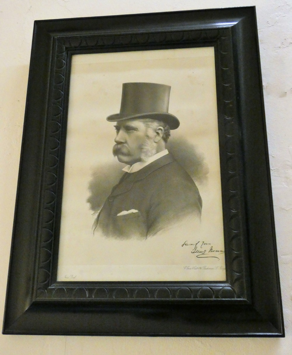 A monochrome antique framed portrait print depicting a Victorian gentleman wearing a top hat, presented in a dark carved wooden frame.