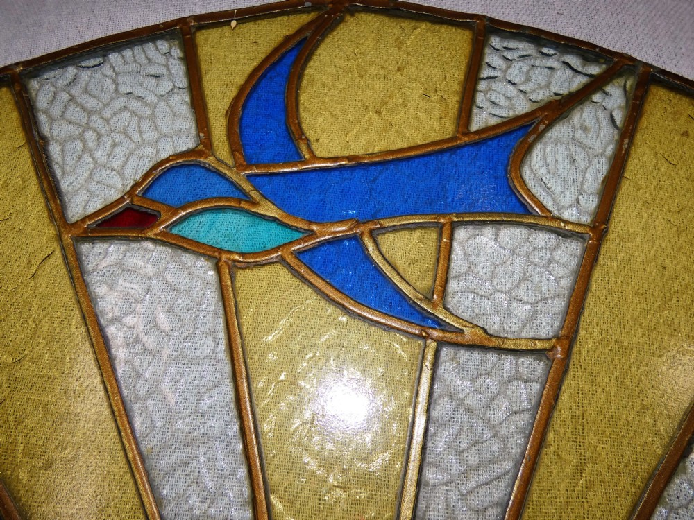 An Art Deco arched leaded stained glass panel depicting a blue bird flying above a sunburst motif over green hills. View III