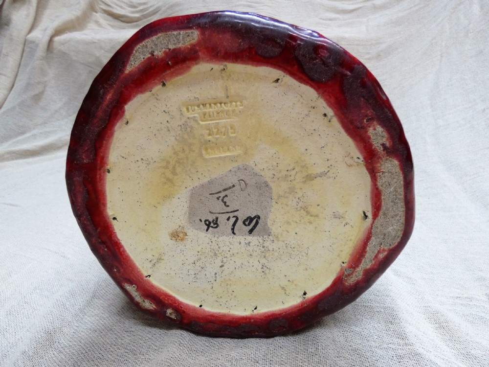 A tall cylindrical ceramic stick stand finished in a deep red glaze featuring an inset green relief panel with three thistle motifs. View VI