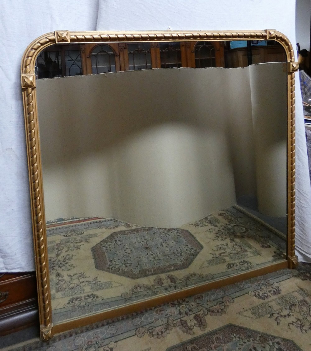 A large Victorian overmantel mirror featuring an arched gold giltwood frame with a rope-twist border and corner rosettes. View II