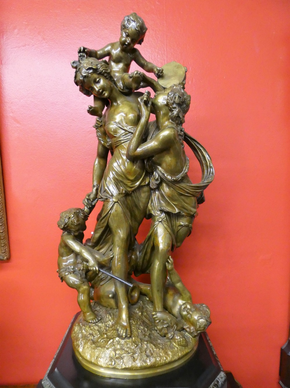 An antique French mantel clock featuring a dark marble base and a patinated bronze figural sculpture of classical figures on top. View II