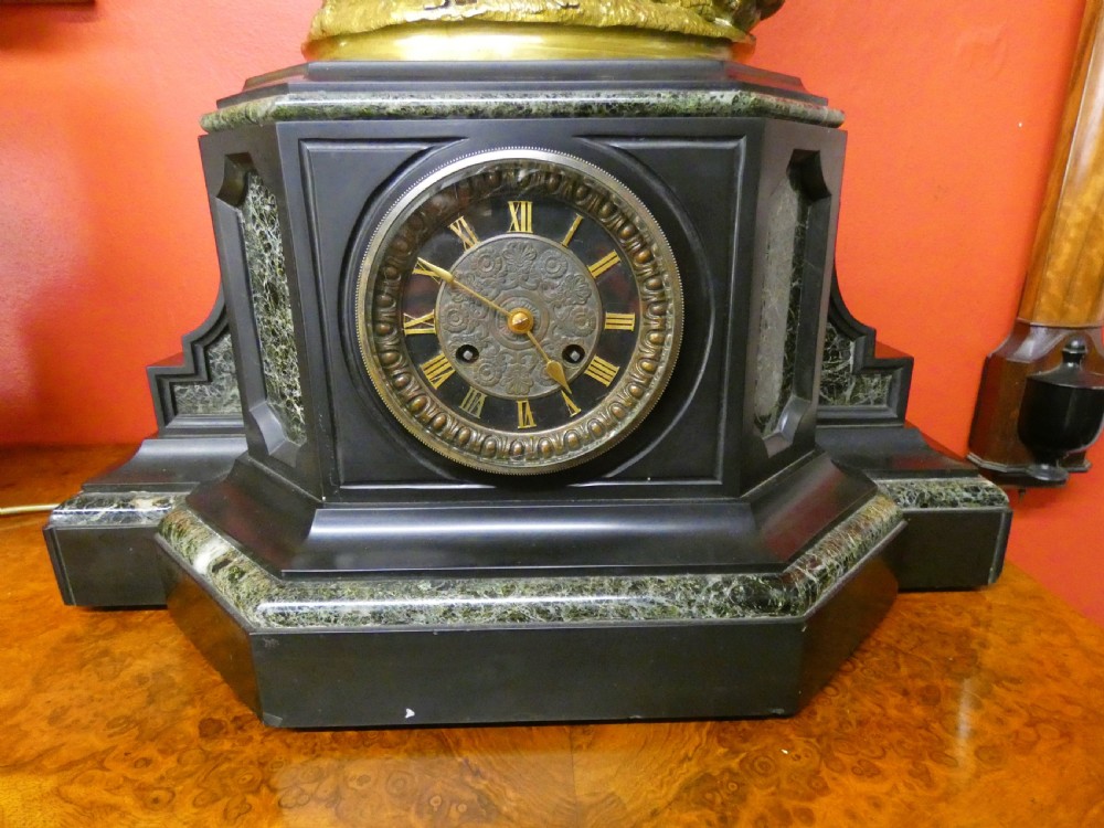An antique French mantel clock featuring a dark marble base and a patinated bronze figural sculpture of classical figures on top. View III