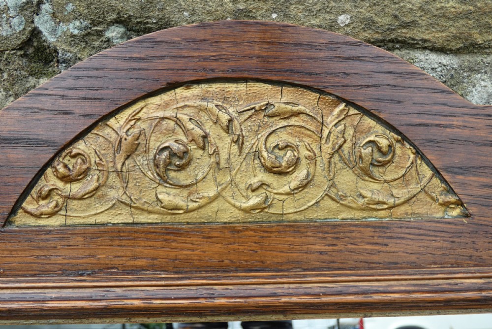 An Arts and Crafts style dark oak wall mirror featuring a carved arched crest and two round turquoise ceramic inlays in the lower corners. View II
