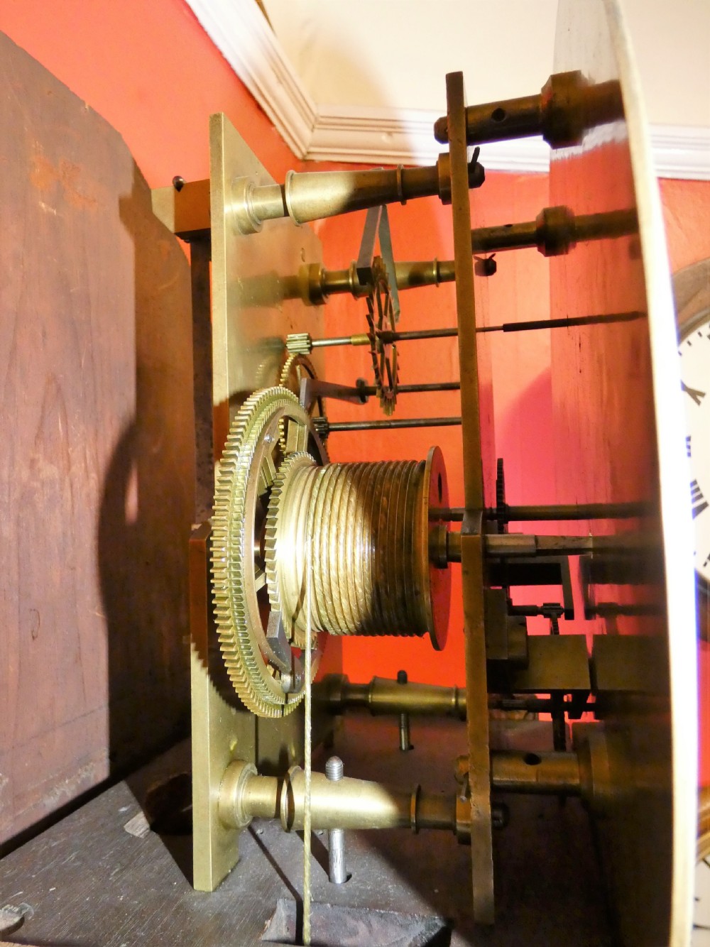 An antique carved dark mahogany regulator longcase clock featuring a circular dial, glass trunk door displaying pendulum weights, and a carved pedestal base. View VII