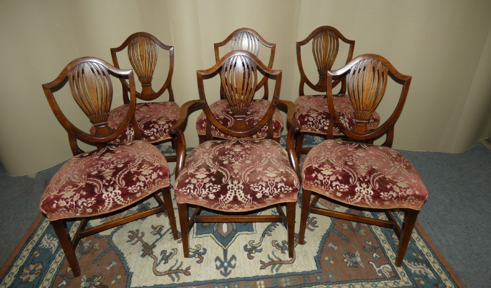 A set of six mahogany Hepplewhite dining chairs featuring carved shield backs and red patterned velvet upholstered seats. View II