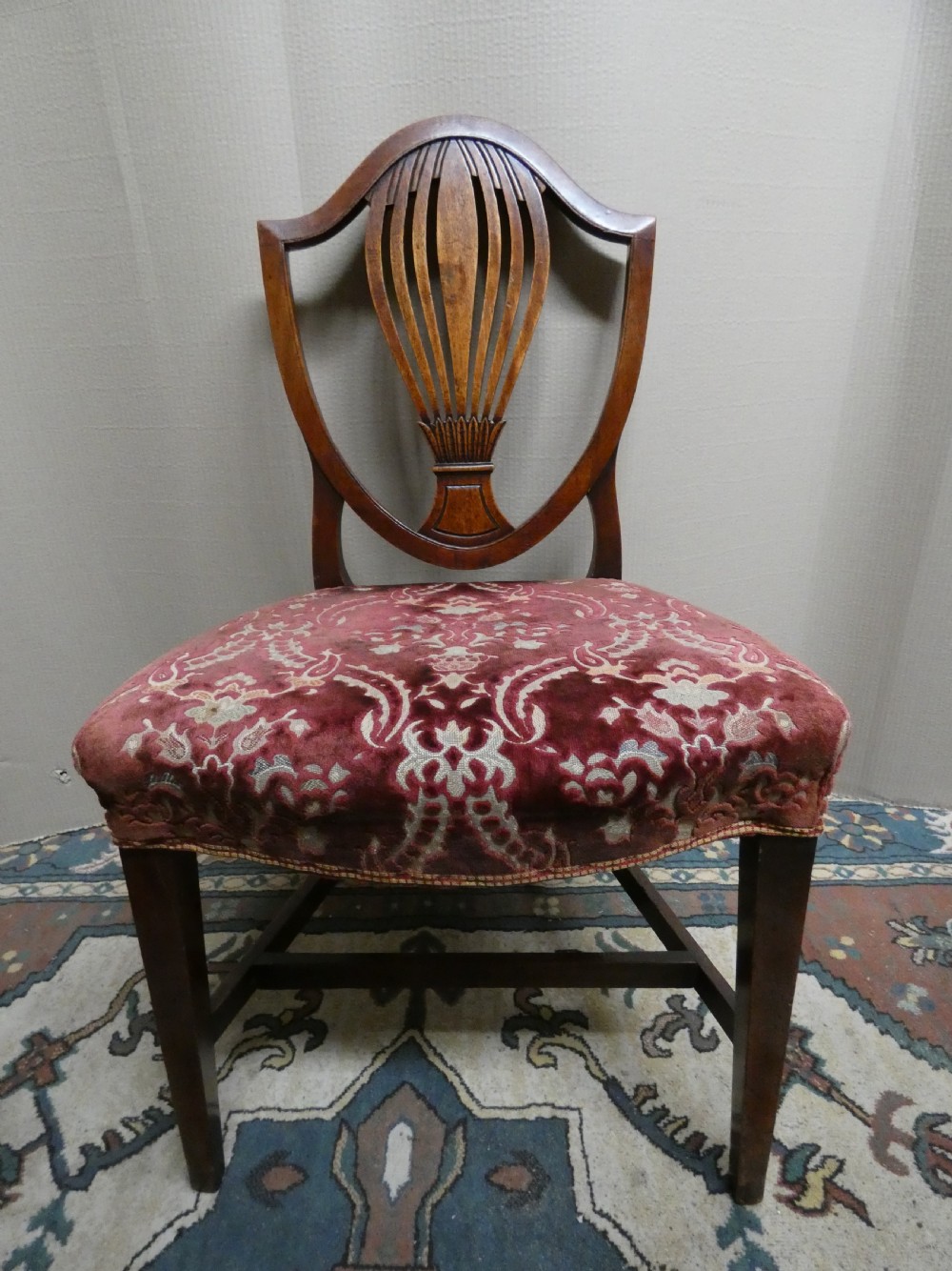 A set of six mahogany Hepplewhite dining chairs featuring carved shield backs and red patterned velvet upholstered seats. View VI