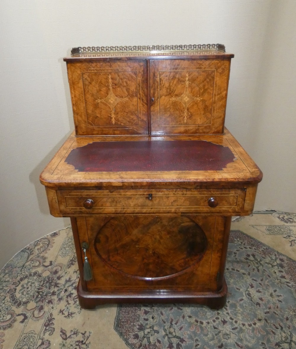 A Victorian burr walnut bonheur du jour writing desk with marquetry inlay, upper twin door cabinet, brass top gallery rail, and burgundy leather writing insert.