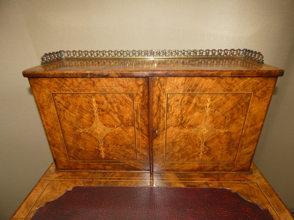 A Victorian burr walnut bonheur du jour writing desk with marquetry inlay, upper twin door cabinet, brass top gallery rail, and burgundy leather writing insert. View II