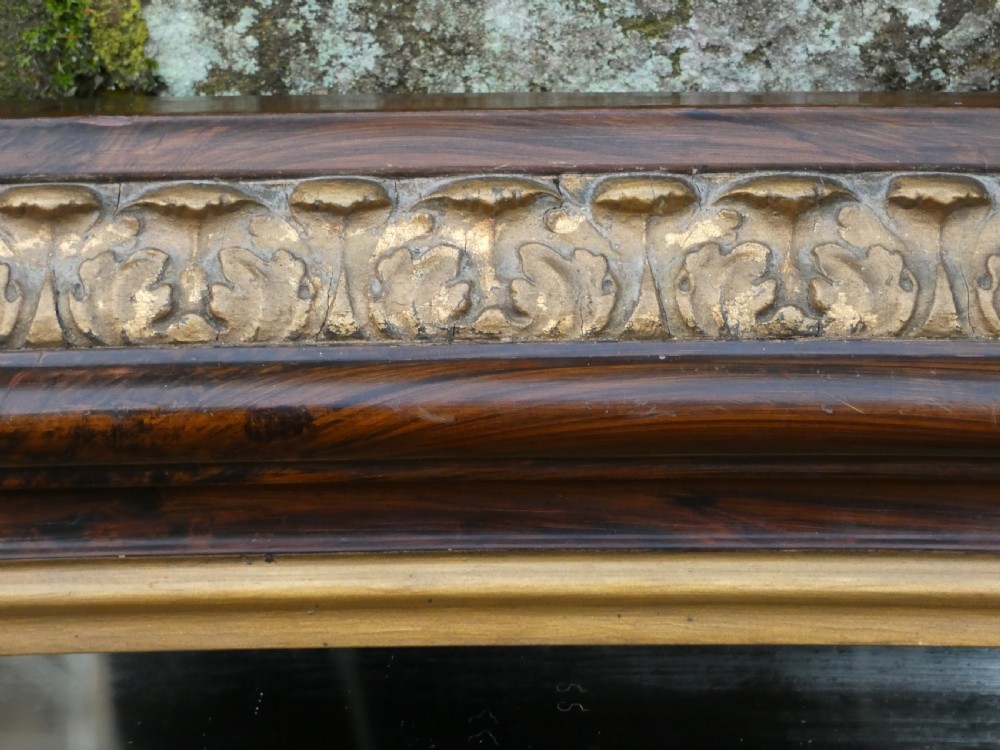 A Victorian arched overmantel mirror featuring a dark timber frame, inner gilt bead moulding, and white porcelain corner feet. View VII
