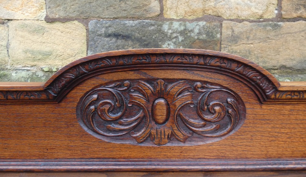 A dark carved oak hall table featuring a detailed relief gallery, two drawers with carved mask handles, turned legs, and a lower shelf. View VI