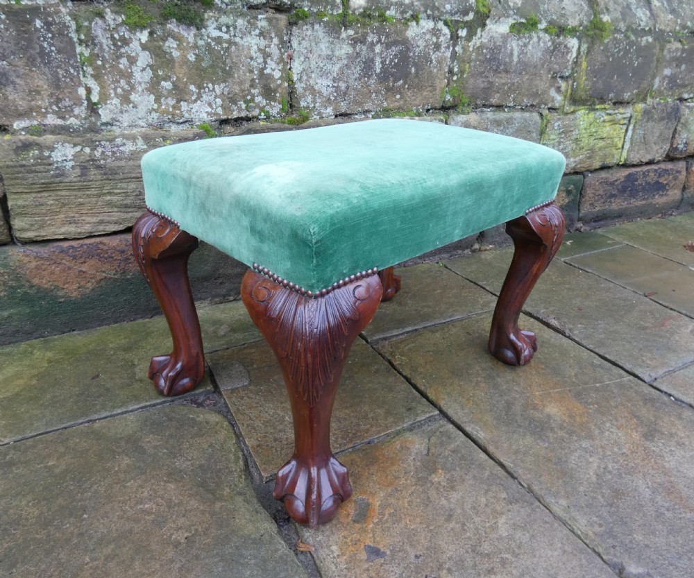 A low rectangular mahogany footstool with green velvet upholstery, studded border detail, and carved cabriole legs with claw and ball feet. View V