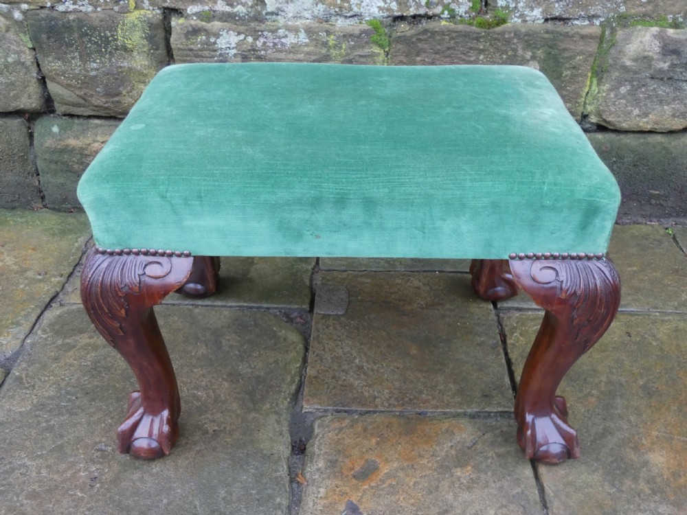 A low rectangular mahogany footstool with green velvet upholstery, studded border detail, and carved cabriole legs with claw and ball feet. View VII