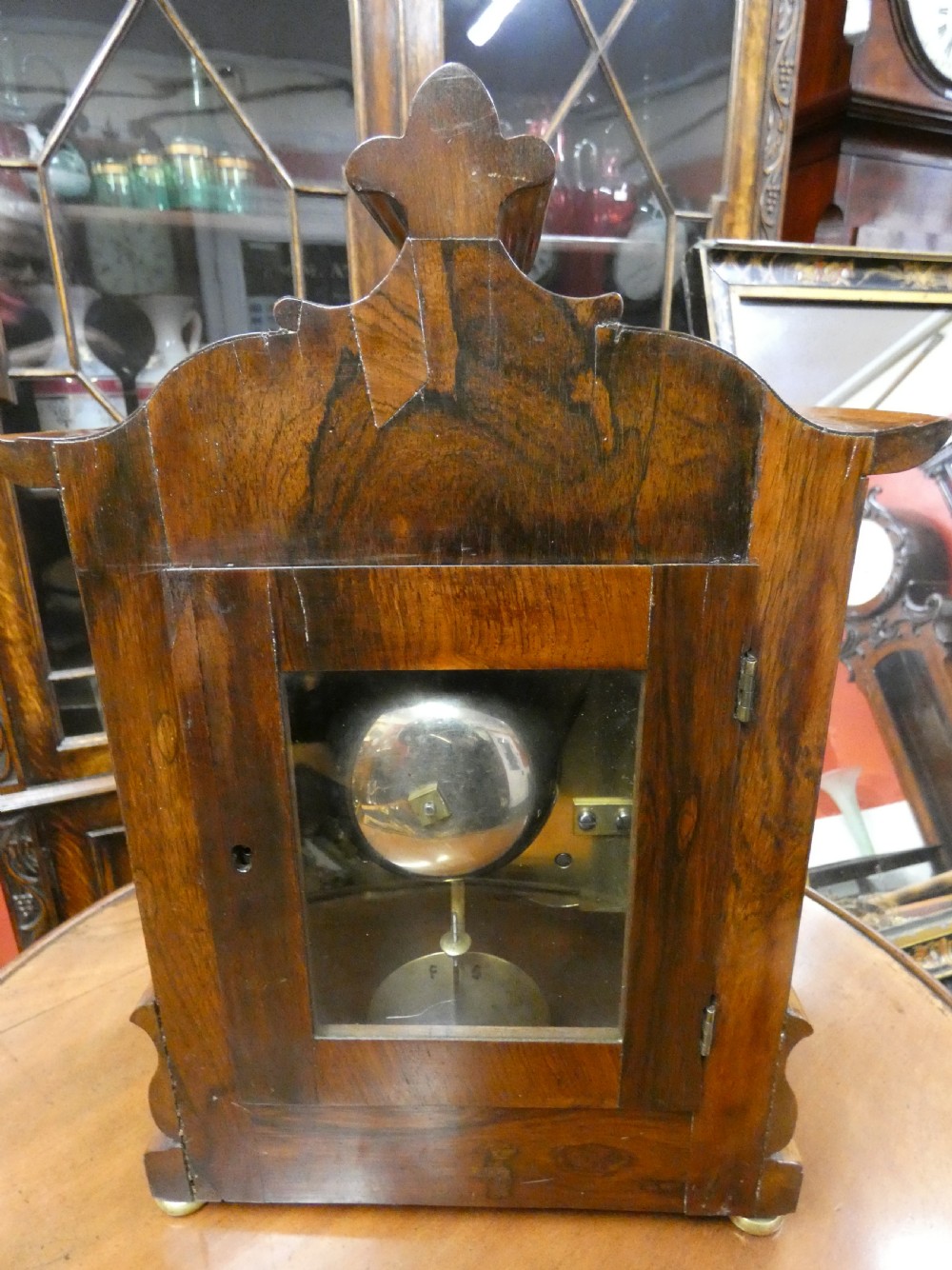 A William IV wooden bracket clock with carved foliate corner accents, brass scroll inlay, and a round dial displaying Roman numerals. View VIII