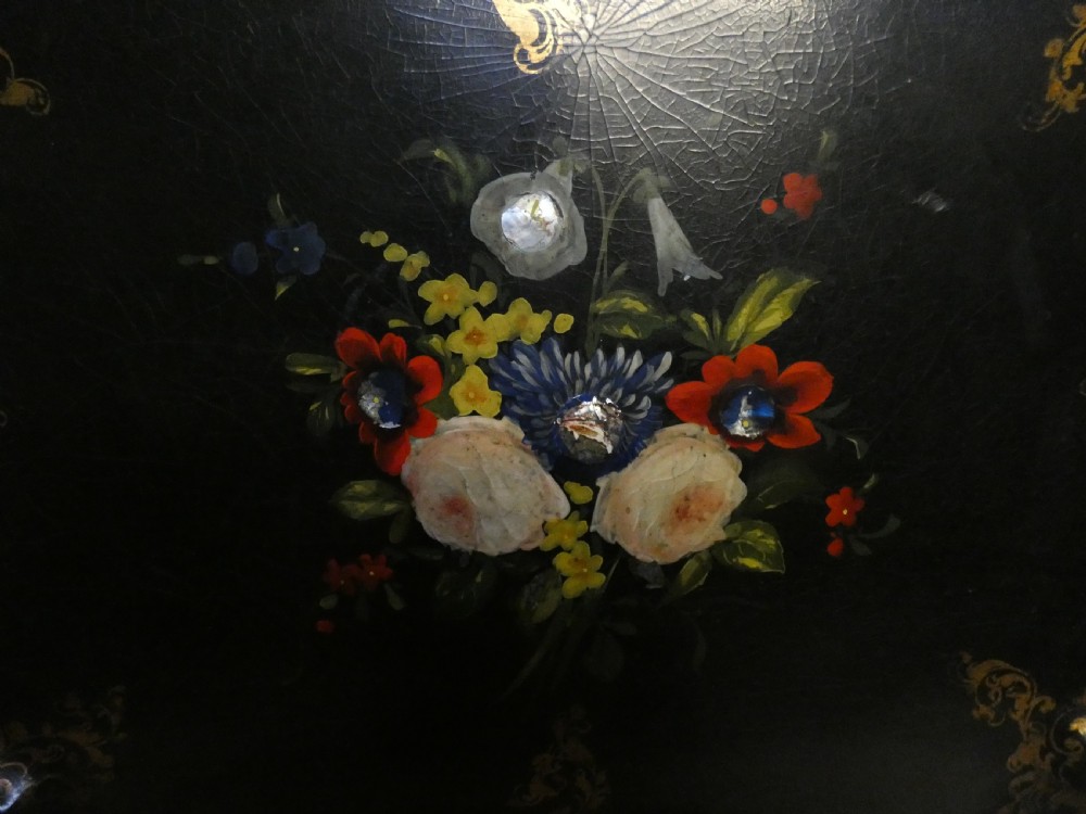 A black Victorian papier-mache serving tray featuring a scalloped rim, gilded scrollwork ornamentation, and a hand-painted floral centrepiece inlaid with mother-of-pearl. View II