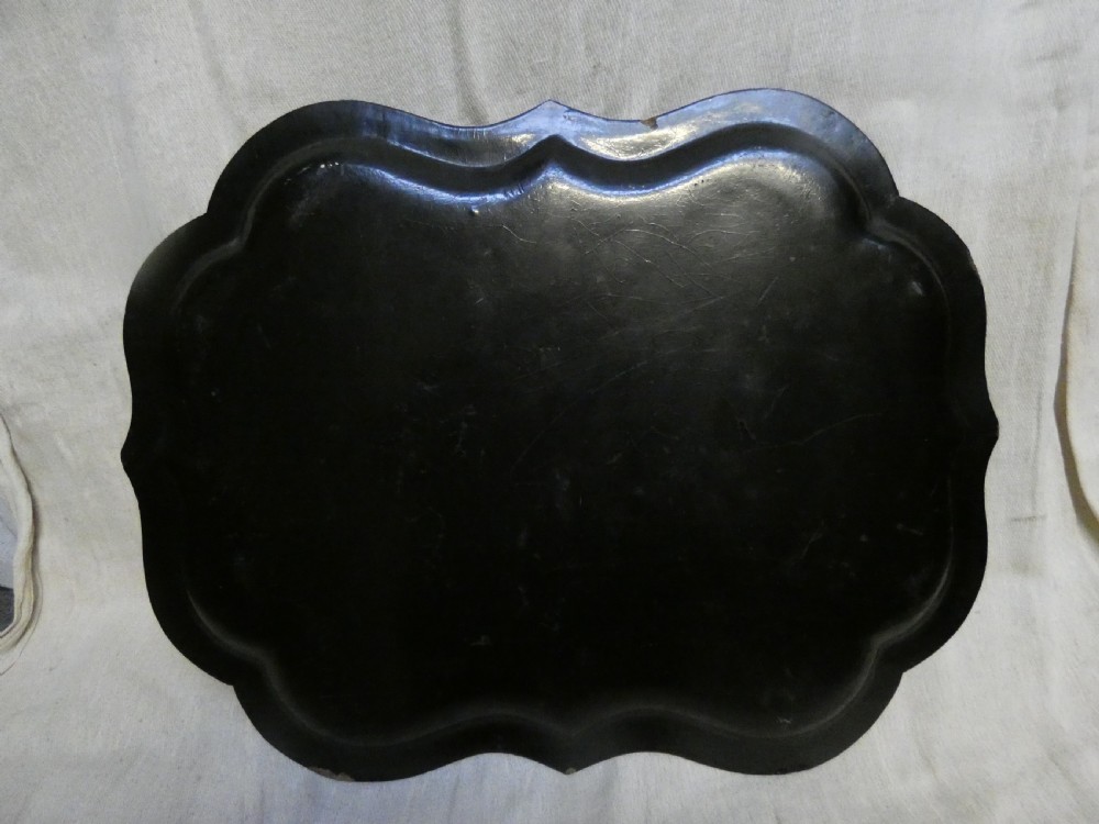A black Victorian papier-mache serving tray featuring a scalloped rim, gilded scrollwork ornamentation, and a hand-painted floral centrepiece inlaid with mother-of-pearl. View V