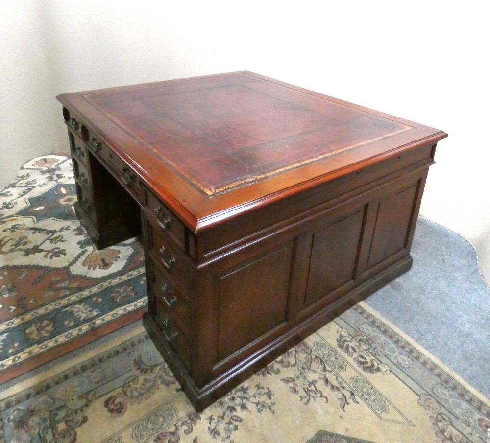A large mahogany partners desk featuring a brown leather-inlaid top, twin pedestal drawers, and brass swan-neck handles. View VIII