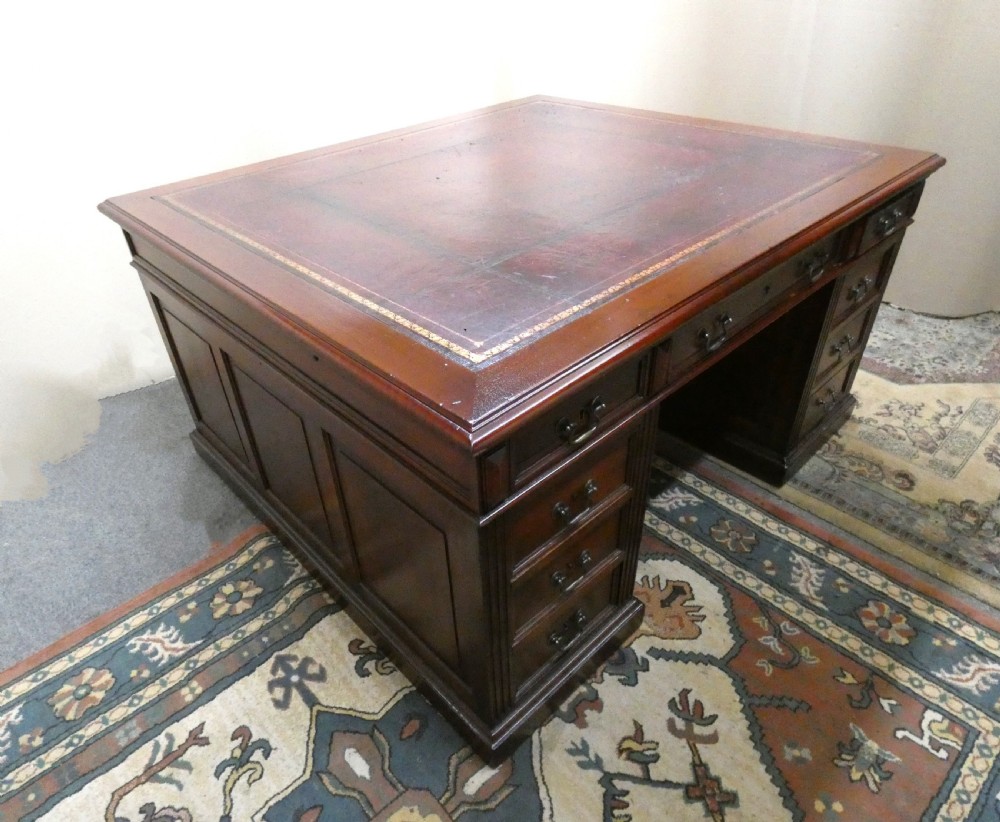 A large mahogany partners desk featuring a brown leather-inlaid top, twin pedestal drawers, and brass swan-neck handles. View IX