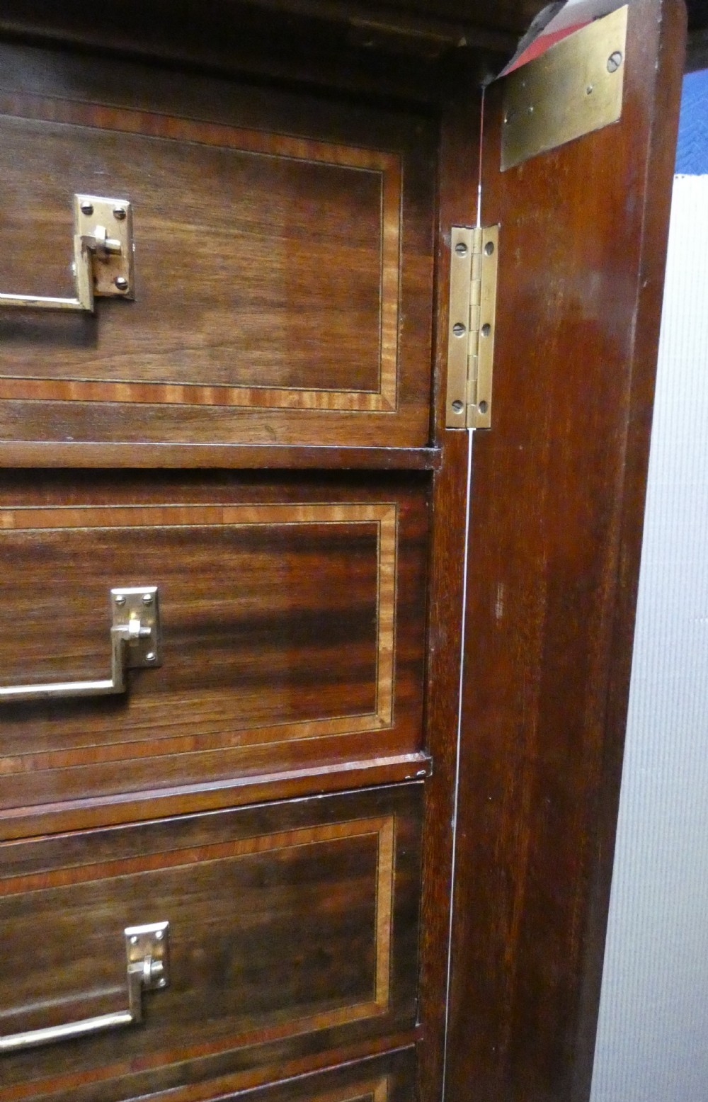 A tall antique mahogany collectors cabinet featuring five shallow upper drawers with brass handles, a hinged side locking bar, and a two-door lower cupboard resting on cabriole legs. View IV