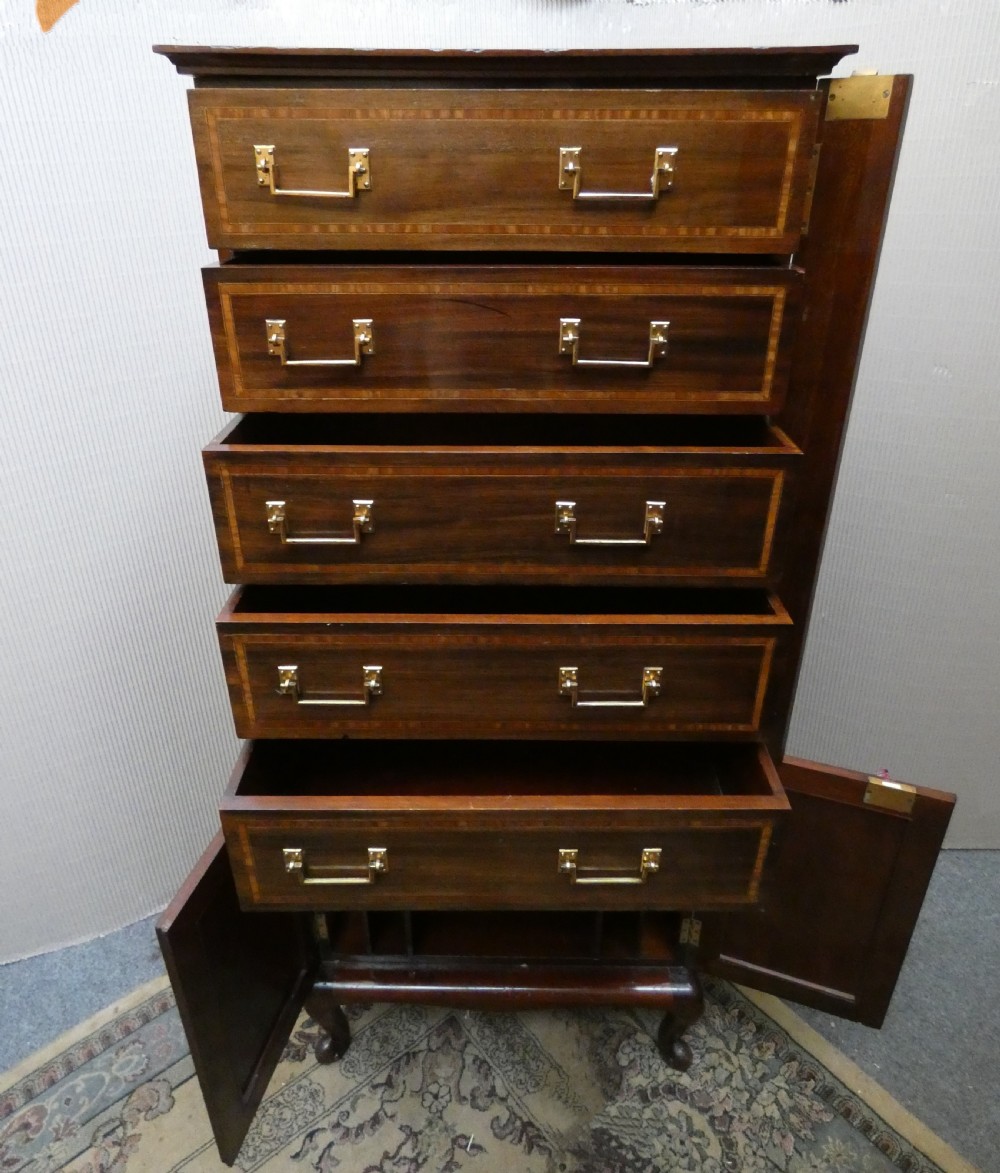 A tall antique mahogany collectors cabinet featuring five shallow upper drawers with brass handles, a hinged side locking bar, and a two-door lower cupboard resting on cabriole legs. View V