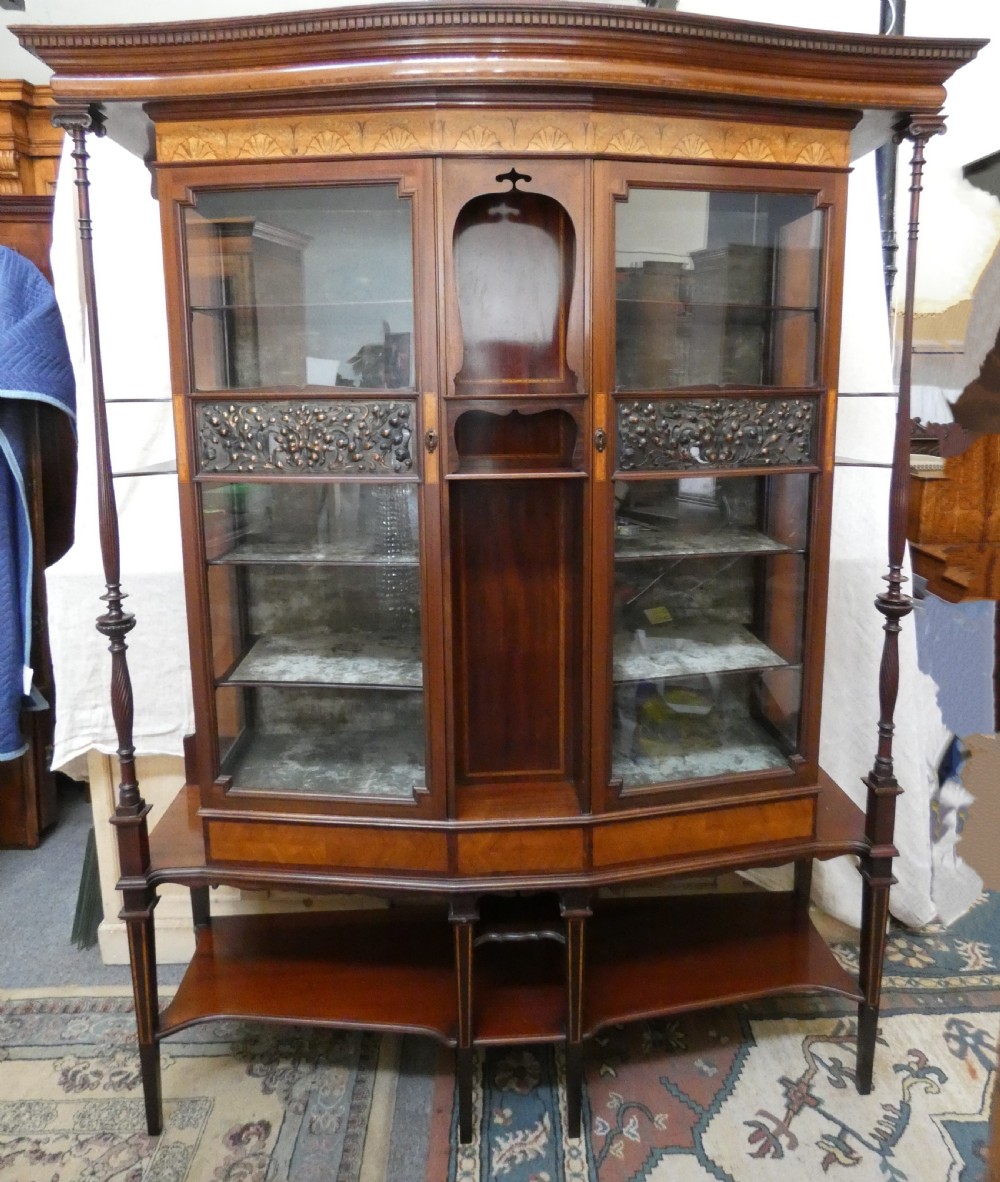 An antique mahogany display cabinet featuring inlaid satinwood decoration, carved floral door panels, glass display sections, and slender corner supports. View II