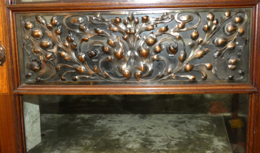 An antique mahogany display cabinet featuring inlaid satinwood decoration, carved floral door panels, glass display sections, and slender corner supports. View V