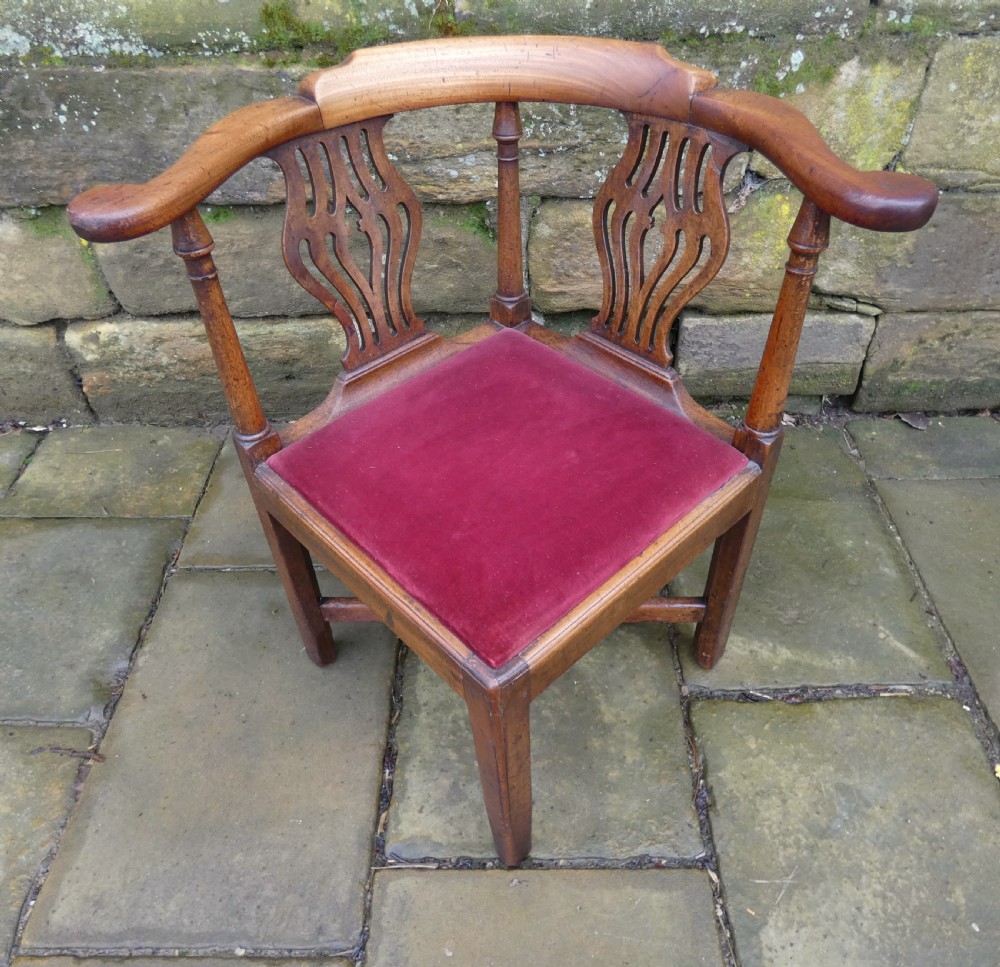 An antique Georgian mahogany corner chair featuring a curved horseshoe armrest, two pierced vase-shaped splats, turned uprights, and a red velvet upholstered seat. View II