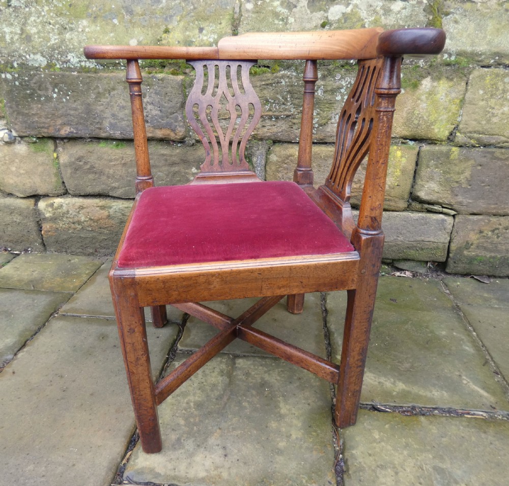 An antique Georgian mahogany corner chair featuring a curved horseshoe armrest, two pierced vase-shaped splats, turned uprights, and a red velvet upholstered seat. View IV