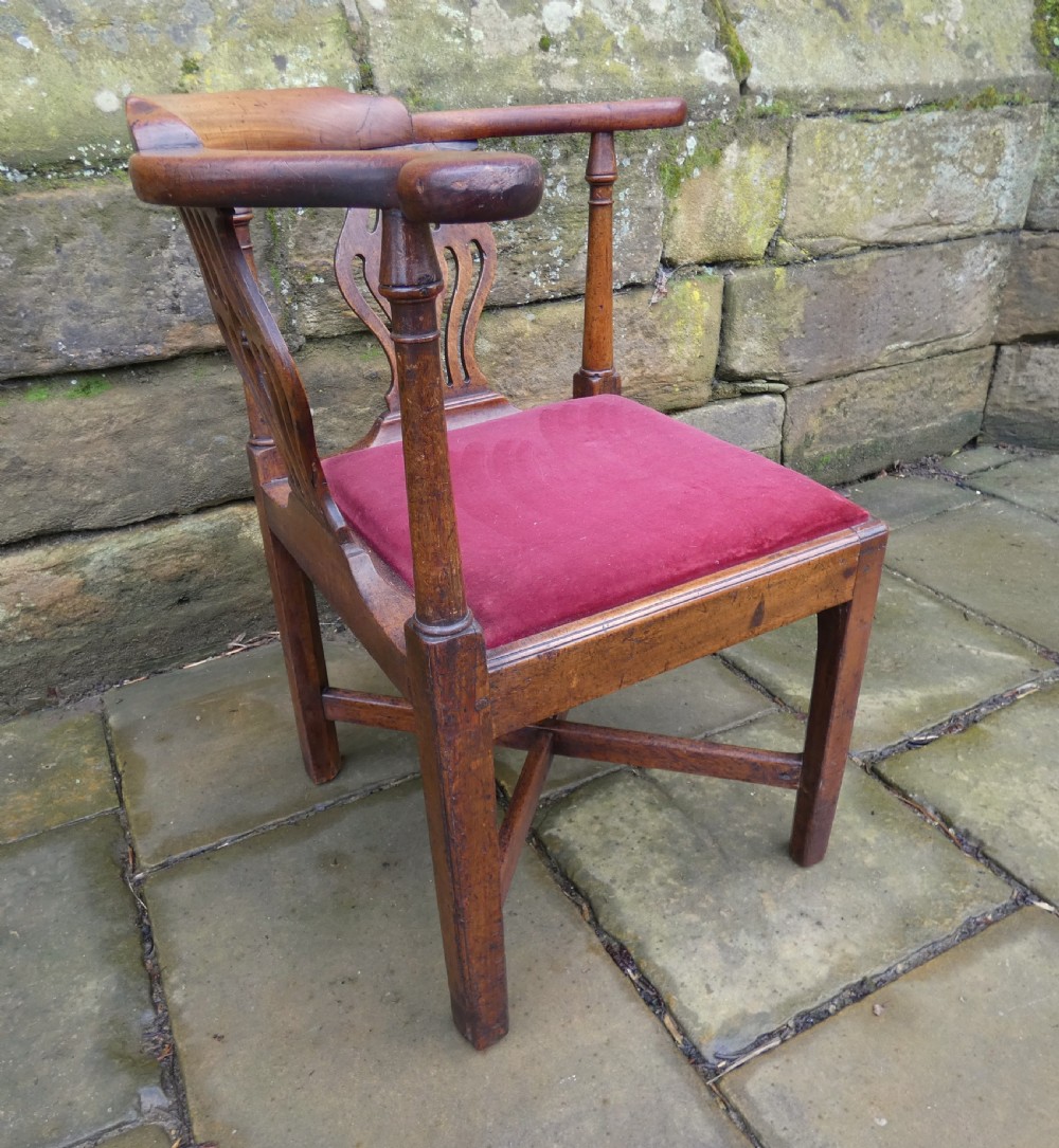 An antique Georgian mahogany corner chair featuring a curved horseshoe armrest, two pierced vase-shaped splats, turned uprights, and a red velvet upholstered seat. View V