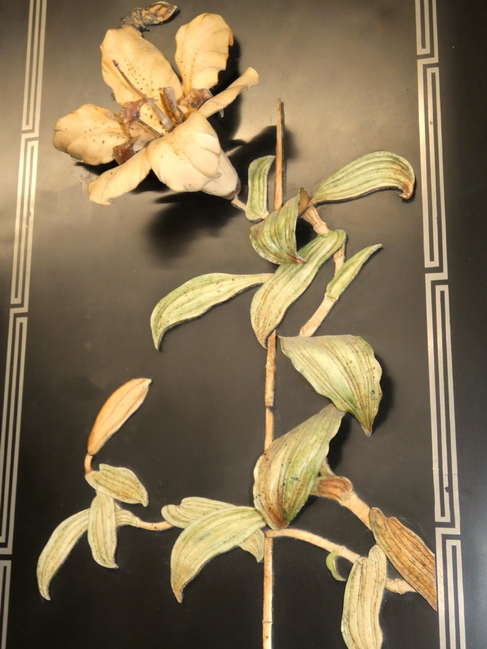 A pair of rectangular Japanese Meiji period black lacquer wall panels featuring high-relief botanical carvings of an iris and a lily within carved wooden frames. View IV