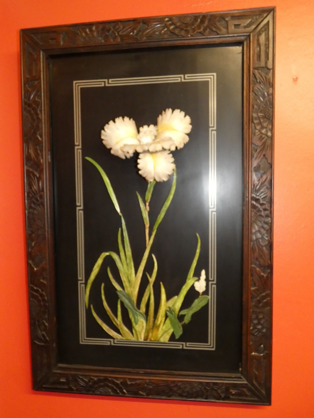 A pair of rectangular Japanese Meiji period black lacquer wall panels featuring high-relief botanical carvings of an iris and a lily within carved wooden frames. View V