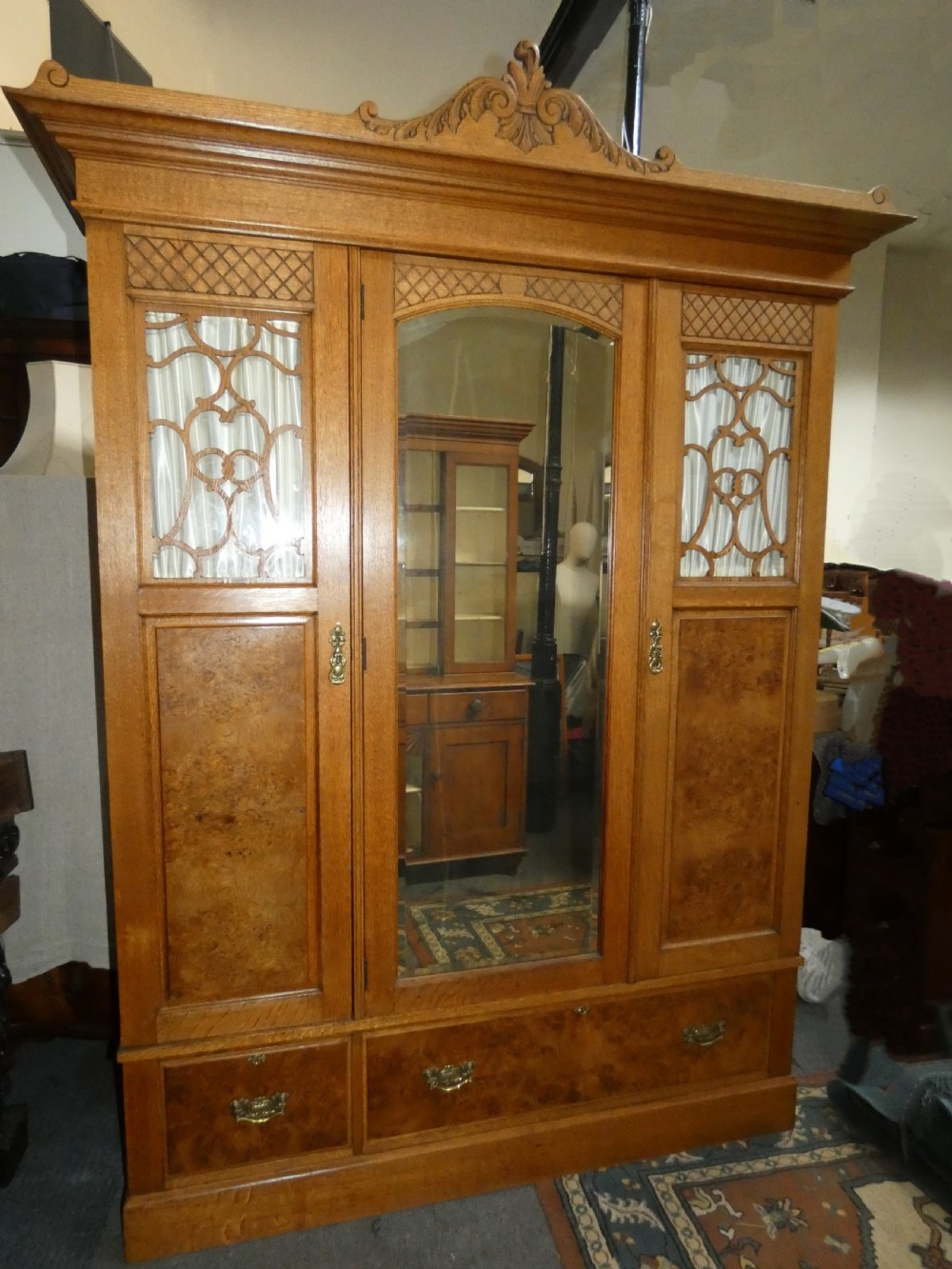 An Edwardian oak bedroom suite featuring a large three-door wardrobe with a central mirrored panel alongside a matching carved dressing table. View II