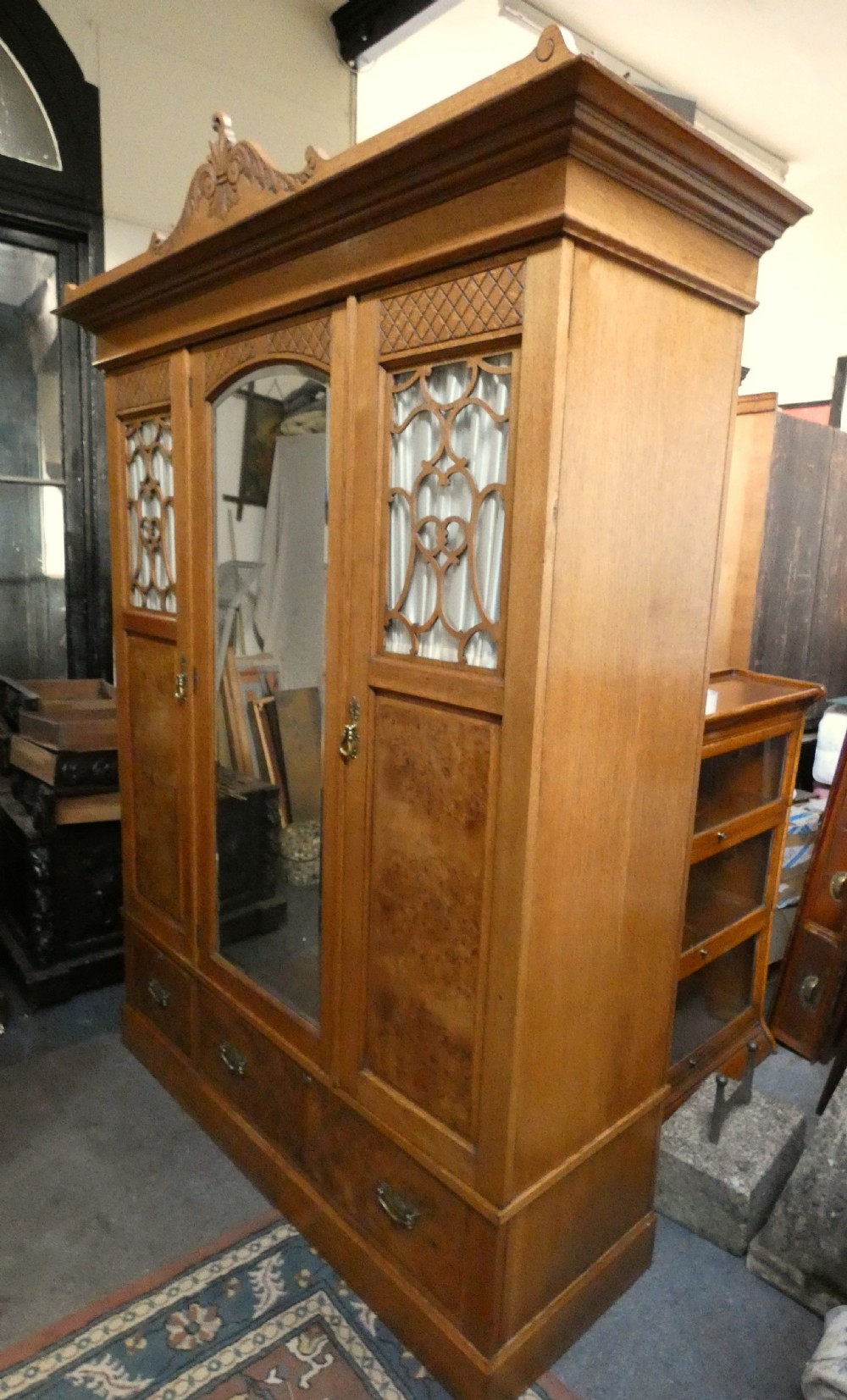 An Edwardian oak bedroom suite featuring a large three-door wardrobe with a central mirrored panel alongside a matching carved dressing table. View VIII