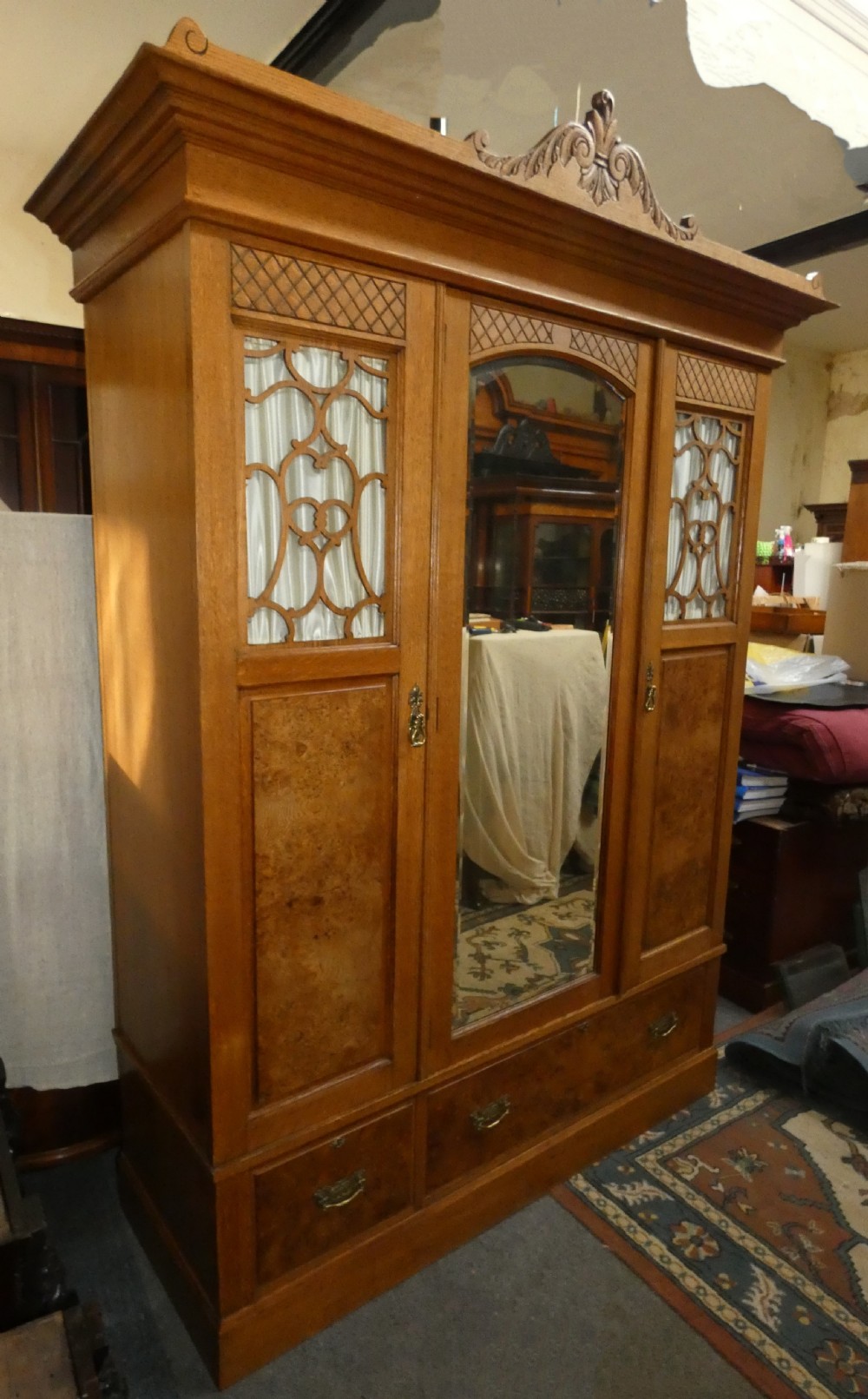 An Edwardian oak bedroom suite featuring a large three-door wardrobe with a central mirrored panel alongside a matching carved dressing table. View IX