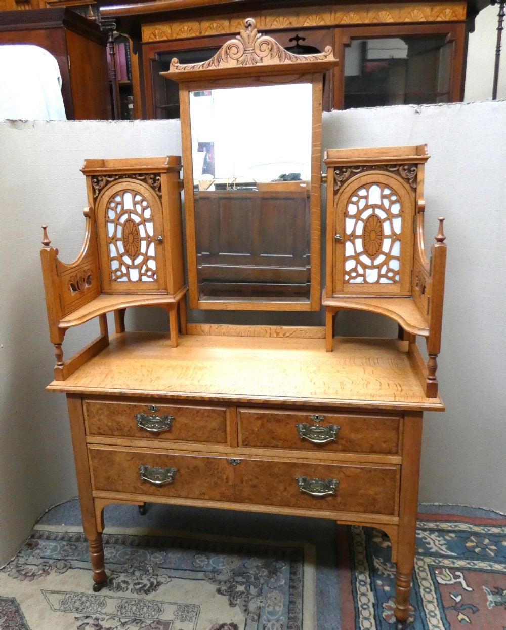 An Edwardian oak bedroom suite featuring a large three-door wardrobe with a central mirrored panel alongside a matching carved dressing table. View X