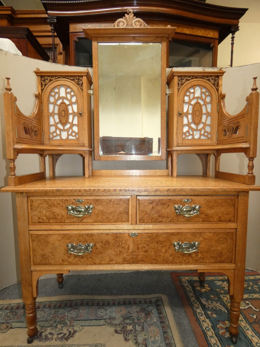 An Edwardian oak bedroom suite featuring a large three-door wardrobe with a central mirrored panel alongside a matching carved dressing table. View XI