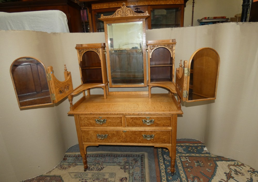 An Edwardian oak bedroom suite featuring a large three-door wardrobe with a central mirrored panel alongside a matching carved dressing table. View XIII