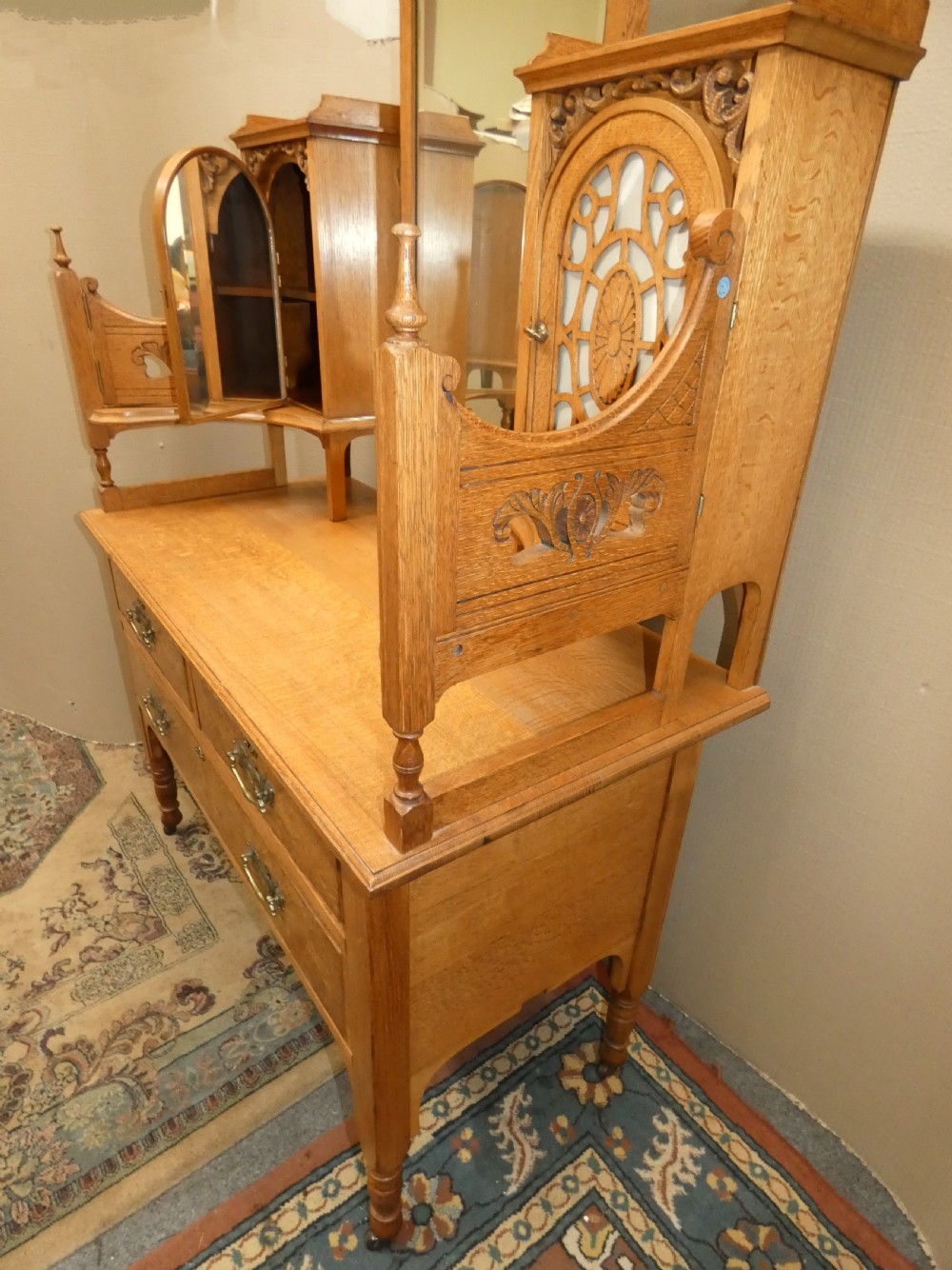 An Edwardian oak bedroom suite featuring a large three-door wardrobe with a central mirrored panel alongside a matching carved dressing table. View XIV