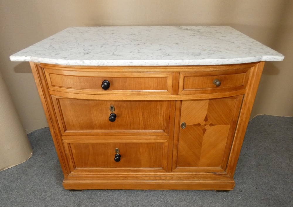 A 19th-century timber washstand featuring a white marble top, three drawers with turned knobs, and a side cupboard door with geometric parquetry inlay.