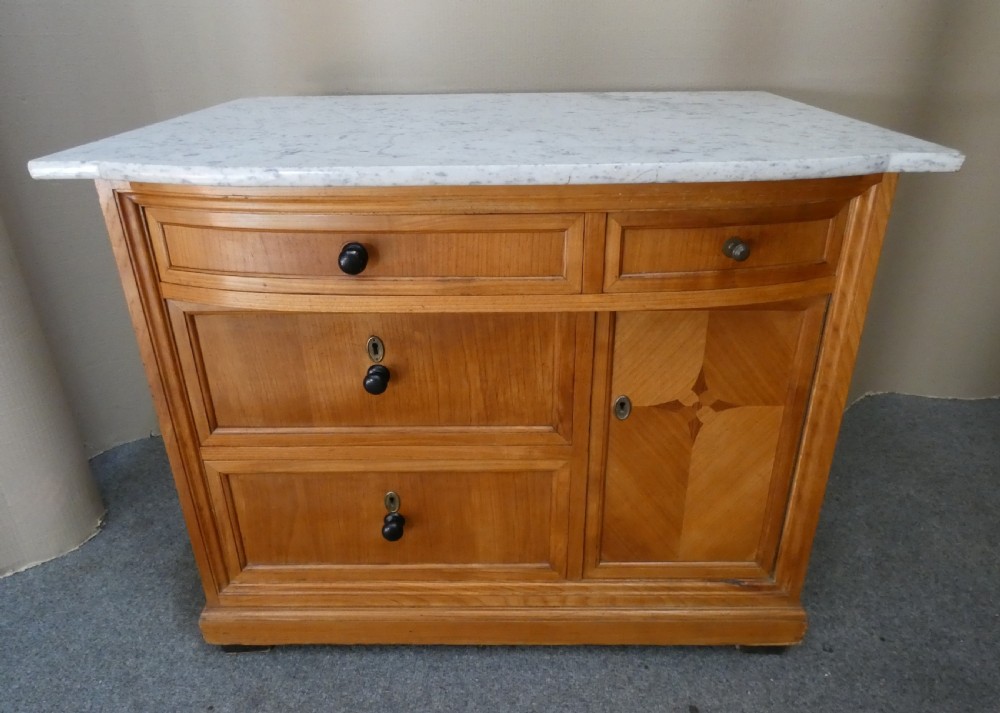A 19th-century timber washstand featuring a white marble top, three drawers with turned knobs, and a side cupboard door with geometric parquetry inlay. View VII