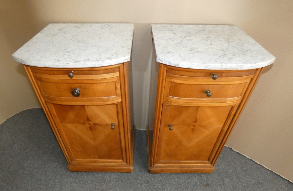 A pair of satinwood bedside cabinets with white marble tops, single drawers, pull-out slides, and marquetry inlaid cupboard doors. View II