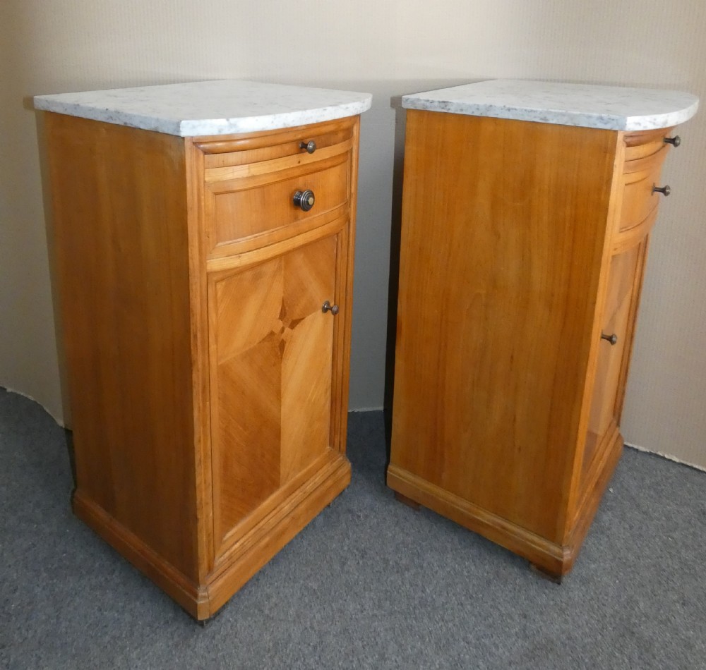 A pair of satinwood bedside cabinets with white marble tops, single drawers, pull-out slides, and marquetry inlaid cupboard doors. View VII