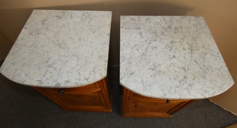 A pair of satinwood bedside cabinets with white marble tops, single drawers, pull-out slides, and marquetry inlaid cupboard doors. View IX