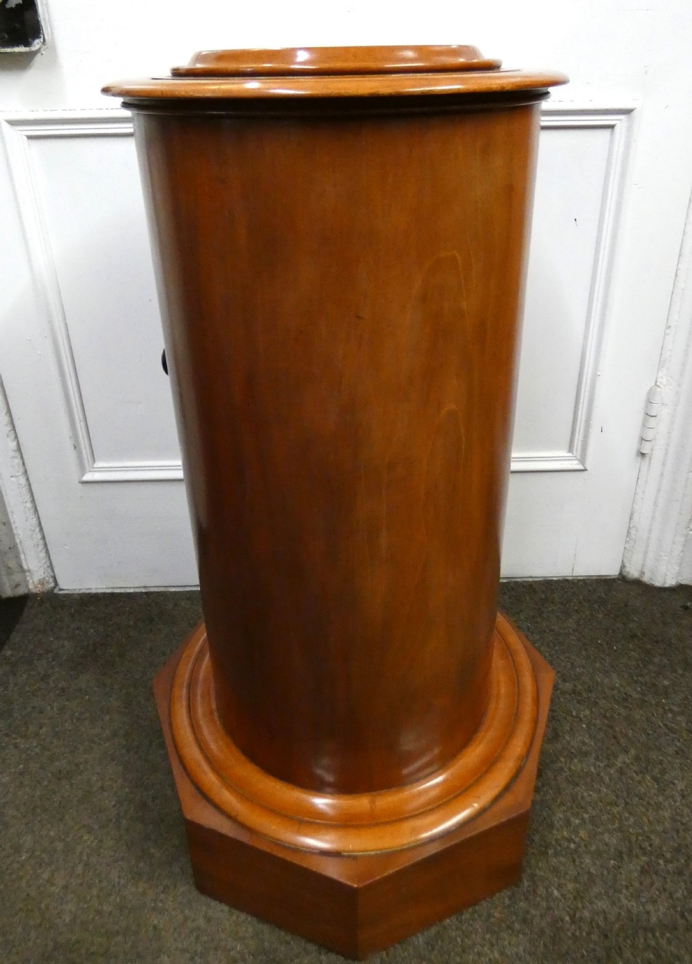 A cylindrical mahogany pot cupboard featuring a stepped circular top, a single curved door with a turned wooden knob, and an octagonal base. View II