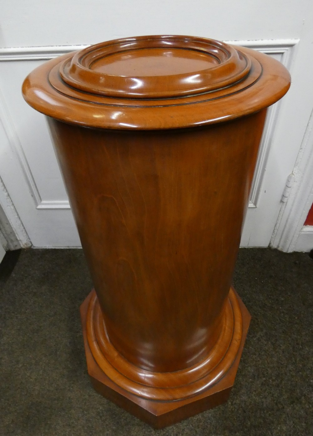 A cylindrical mahogany pot cupboard featuring a stepped circular top, a single curved door with a turned wooden knob, and an octagonal base. View VI