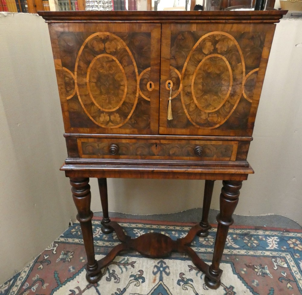 A late 17th-century olive wood cabinet on stand featuring oval oyster veneer patterns, a single drawer, and turned legs with a shaped stretcher.